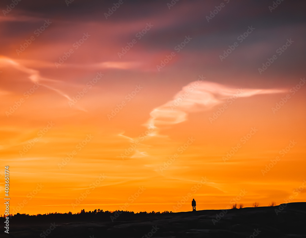 Small silhouette of a man standing alone on hill at sunset. Evening. Human silhouette watching the colorful sky at sunrise. Morning. Concept of privacy and harmony. Minimalism. Negative space. Horizon