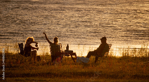 personas divirti  ndose y conversando a a la orilla de un lago durante un atardecer tranquilo de verano caluroso