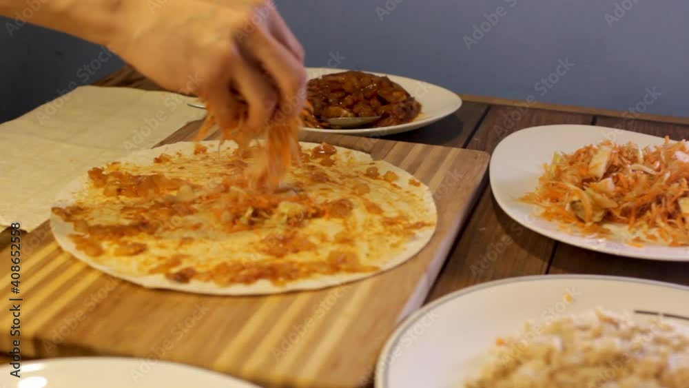close-up of the hands, sprinkle the filling on the pizza dough. the family prepares food in the kitchen close-up of the hands, sprinkle the filling on the pizza dough. the family prepares food in the kitchen