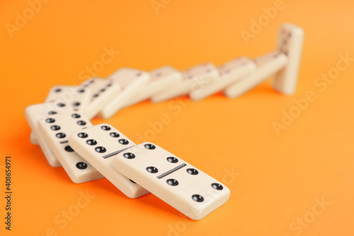 White domino tiles falling on orange background photo