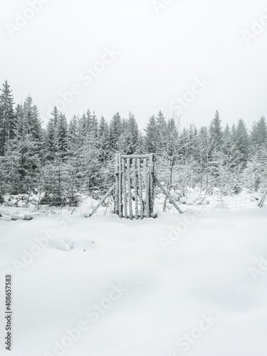 Beautiful snowy white winter landscape with fence and the door and forest on background. Brdy, Czech Republic.