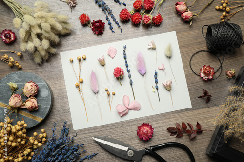Flat lay composition with beautiful dry flowers on wooden background