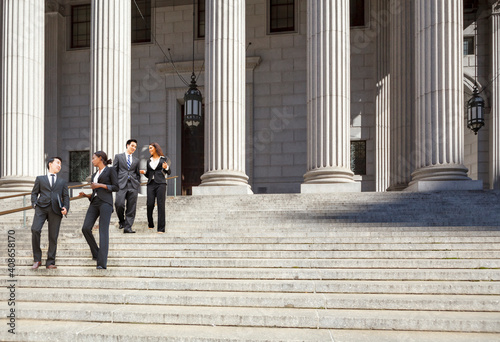 Four well dressed professionals walk down steps in discussion outside of a courthouse. Could be lawyers, business people etc. photo