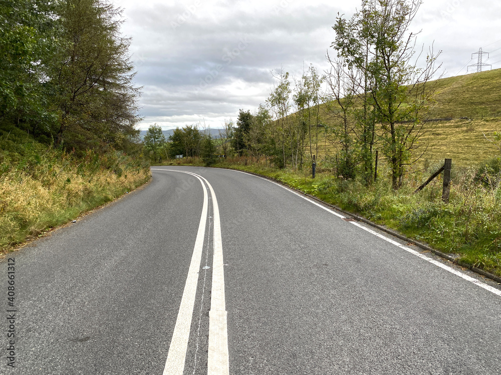 Looking along the, Huddersfield Road, with trees, hills and a cloudy sky in, Rochdale, Lancashire, UK