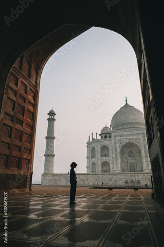 Young woman looking at Taj Mahal from inside Kau Ban Mosque during sunrise, Agra, India photo