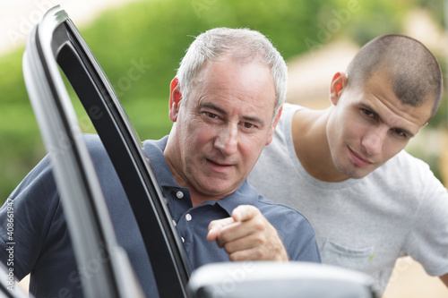 father pointing to car wingmirror son stood behind him