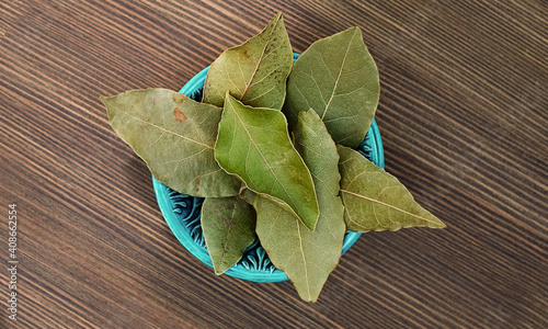 Bay leaves in blue handmade cup on wooden background. Laurel for cooking photo