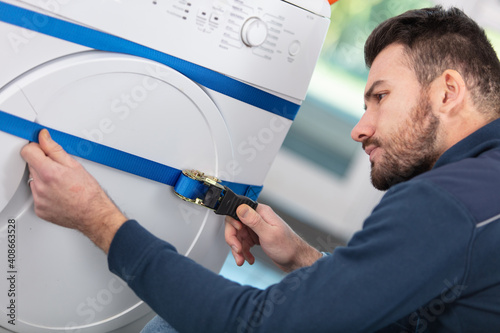 delivery man adjusting strap around washing machine photo