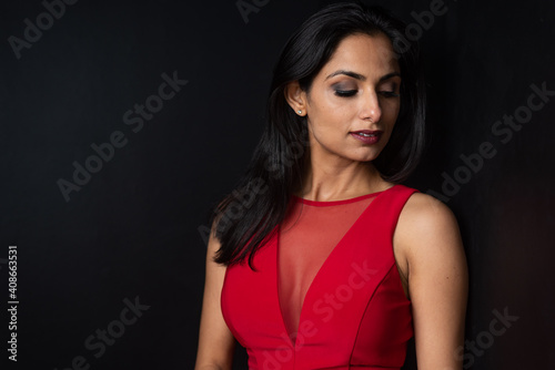 Studio images of beautiful Asian Indian woman wearing red dress on black background. 