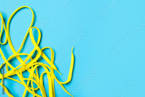 Yellow shoelaces on light blue background, flat lay. Space for text