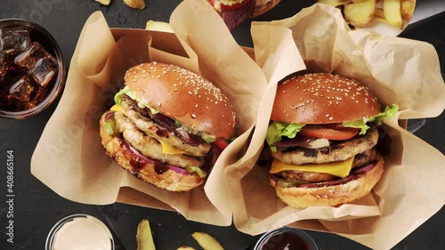 Yummy big cheeseburger with double juicy cutlet in craft box, top view rotation. Fast food set, burger and fries.
