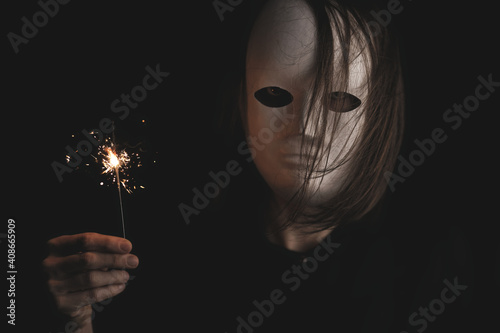 portrait of a woman in a white mask in the dark. photo