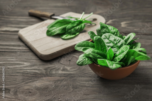 Fresh spinach leaves in a bowl on a rustic wooden table. Selective focus.
