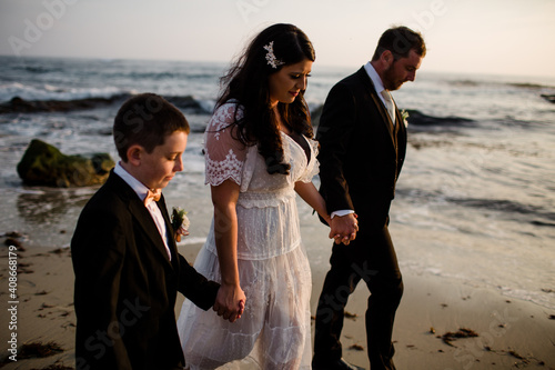 Newlyweds & Nine Year Old Son Walking Along Beach in San Diego photo