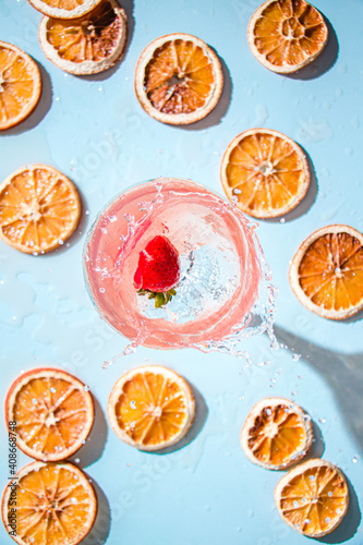 strawberry splashing into cocktail with orange slices