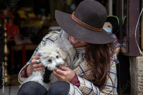 A hatted woman plays with a cute white puppy photo