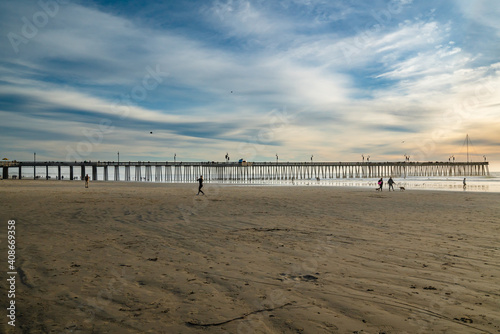 Sunset on Pismo Beach. Wide sandy beach  a long wooden pier  ocean view and beautiful cloudy sky on background