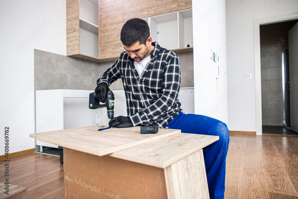 The carpenter finalizing the assembly of the kitchen shelf The carpenter finalizing the assembly of the kitchen shelf