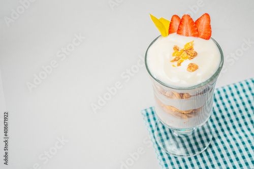 Desayuno de yogurth con fruta en copa de cristal con fresas y cereal sobre tela. photo