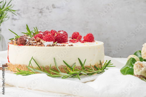 Cheesecake with raspberries, chocolate, hazelnuts and rosemary leaves on kitchen coutertop photo