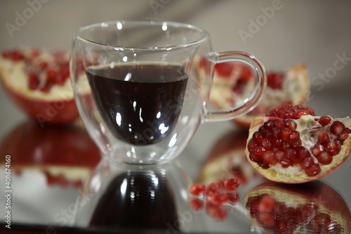 Background image of a broken pomegranate fruit with red seeds and juice in a glass cup.Selective Focus