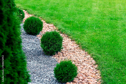 Fotografija Landscape bed of garden with wave ornamental growth cypress bushes gravel mulch by color rock way on a day spring park with green lawn meadow close up details, nobody