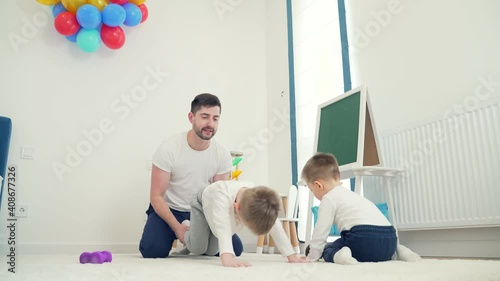 Funny and cheerful young father playing with his son in the nursery. Happy spend time together Leisure on Father's Day. Young family with small kids playing. Dad holds his son in his arms upside down