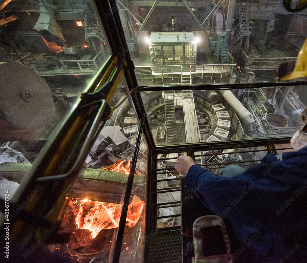 Worker operates in the cabin of a cargo crane at the steel mill