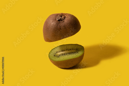 Kiwi fruit with one half floating in air. Yellow background. Creative food concept