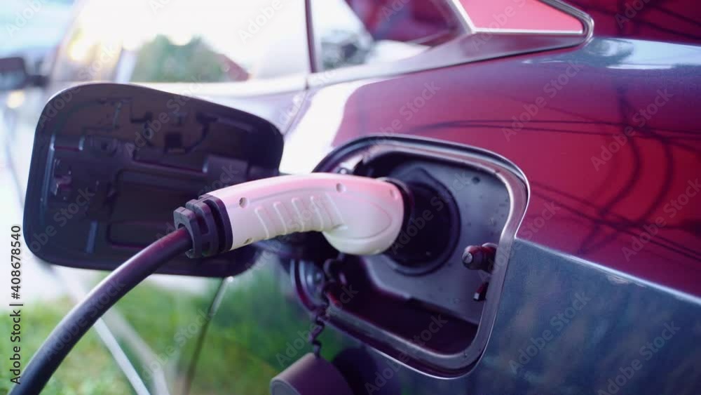 man plugging in electric car to charging station at an electric plug-in vehicle preferred parking in outskirts man plugging in electric car to charging station at an electric plug-in vehicle preferred parking in outskirts