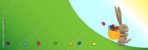 Hase zu Ostern auf einer grünen Wiese mit einem Korb voll bunter Eier die er im Gras auf seinem Weg verliert dabei scheint die Sonne und der Himmel ist strahlend blau