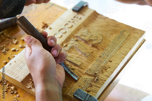 Manos de un hombre tallando con gubias sobre madera, trabajo artesanal 