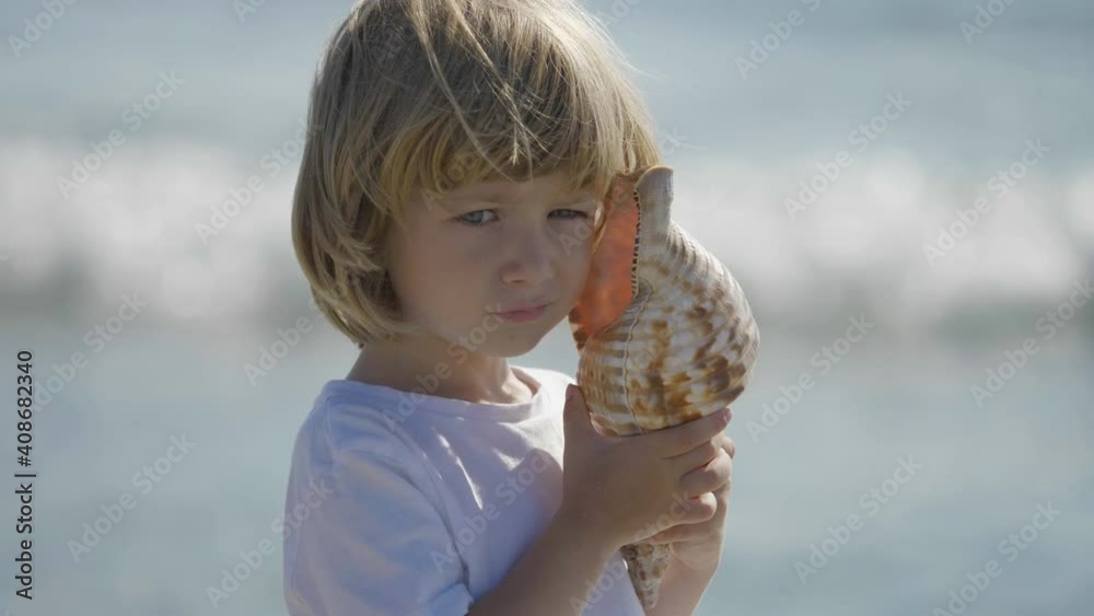 Funny blond hair child with blue eyes portrait hold shell to ear, funny boy look inside conch, sea waving, curious  little boy