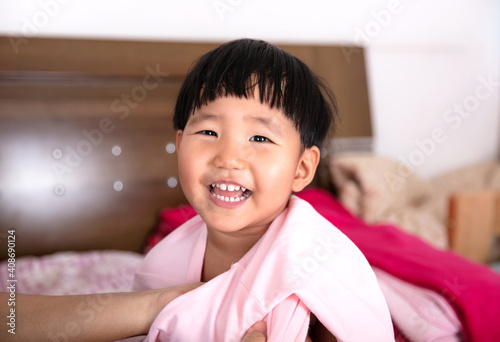 The little girl is wearing a coat on the bed