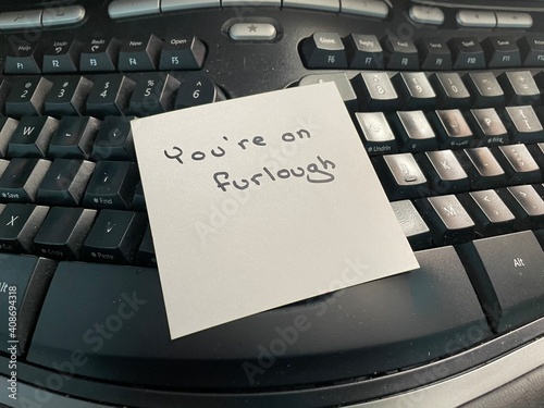 A handwritten note on a computer keyboard stating you’re on furlough. Furlough is a leave of absence or a temporary layoff from work