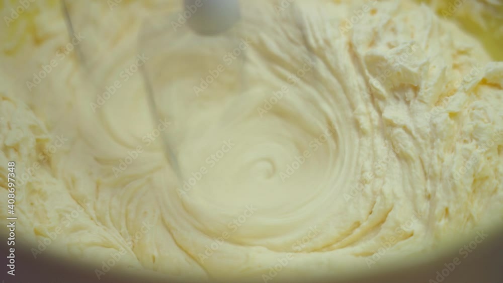 Whips up the cream for the cake with an electric mixer close-up.