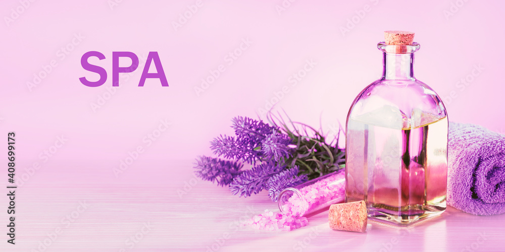 Spa products with lavender flowers on a pink table.