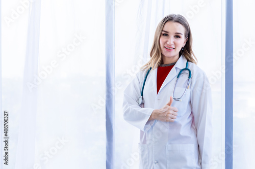 young female doctor therapeutic advising with positive emotions showing thumbs up with smiley face very good on wooden table in Hospital background