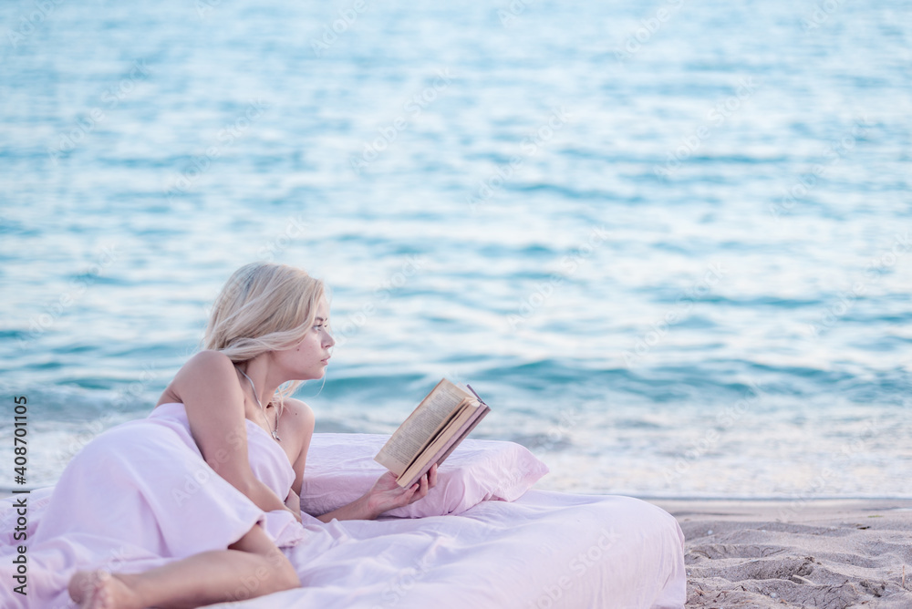 Relax concept. Cozy and comfortable bed near the sea. Summer vacations still life. Woman reading a book.
