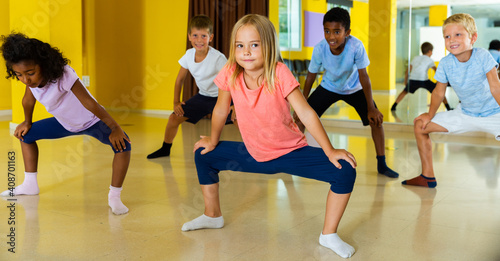 Group of children participating in dance class, following their teacher in dance school.