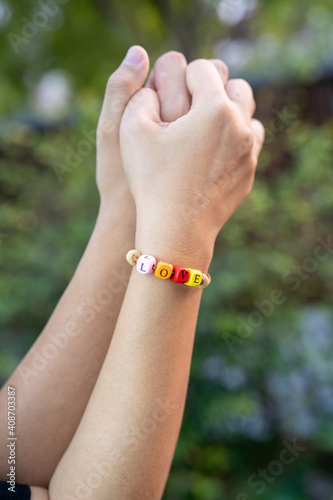 Closeup of couple holding hands, Love word on women Bead bracelet, Valentine concept. © Juraiwan