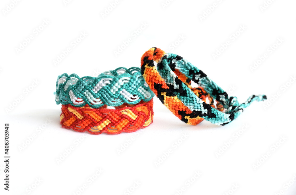 Woven DIY friendship bracelets handmade of embroidery bright thread with knots on white background. colors of fire and water