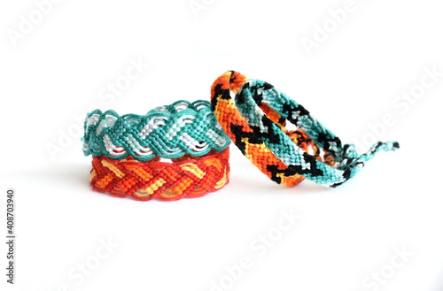 Woven DIY friendship bracelets handmade of embroidery bright thread with knots on white background. colors of fire and water