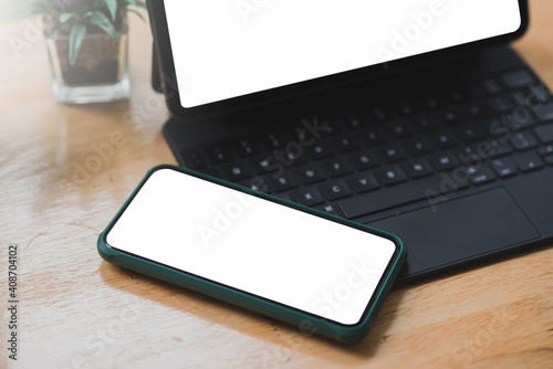 Office stuff with tablet and phone on wooden table.