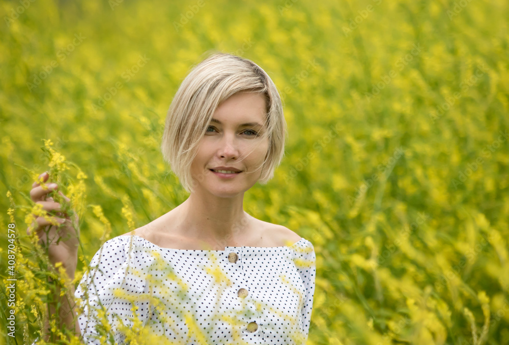 Horizontal portrait of a beautiful woman. A woman stands in a field surrounded by bright yellow flowers. Horizontal portrait of a beautiful woman. A woman stands in a field surrounded by bright yellow flowers.