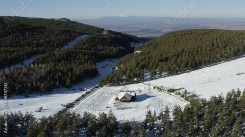 Serene flight over a deserted cabin in an empty ski resort with deep snow.