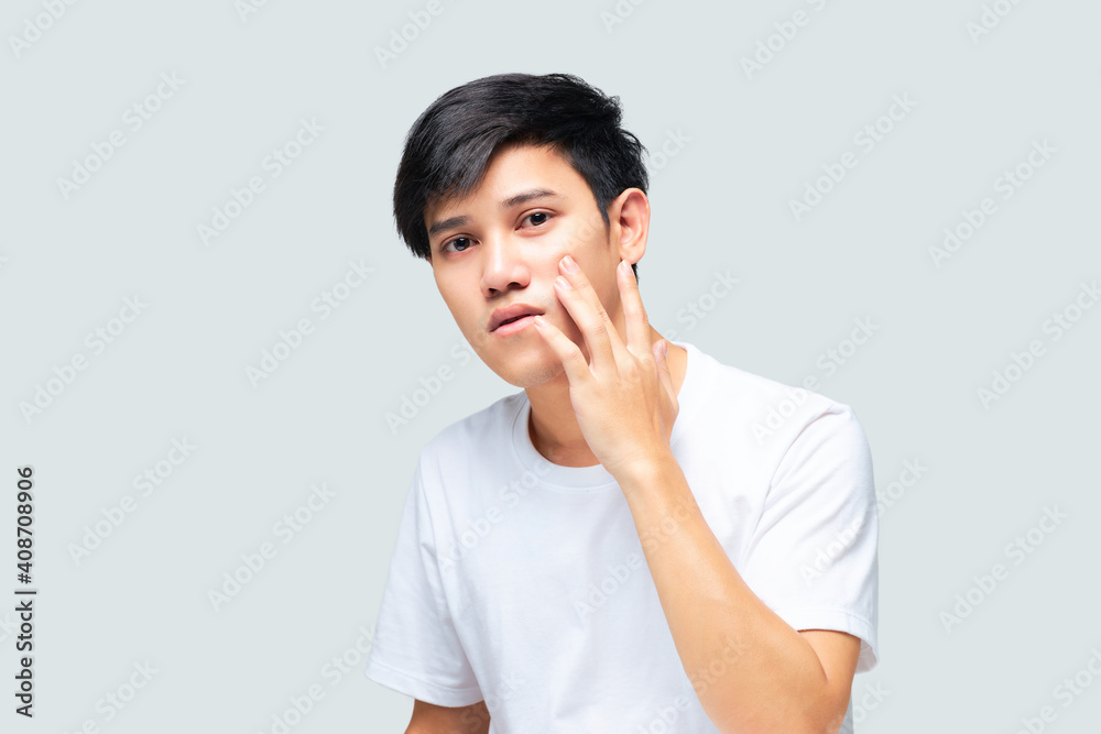 A young man examining the health of his face while looking in the mirror. A young man examining the health of his face while looking in the mirror.