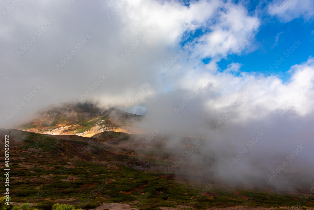 秋の北海道・大雪山で見た、北海岳の山頂にかかる雲と雲間から見える青空