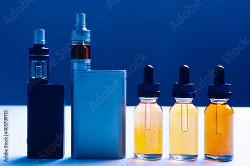 Vape shop concept. Electronic cigarettes and liquids for smoking are nearby. Buying electronic cigarettes in vape shop. Devices for vape on a white table. Concept - online store selling vaping  kits