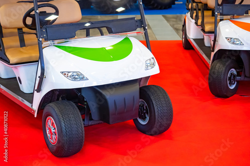 Electric golf cart on the red carpet. Golf machine. Two golf carts at a car show. Concept - electric vehicles. Eco-fueled cars. Renewable energy car sales. White electric car.